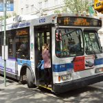 A woman boarding a clean air hybrid electric bus at a city stop