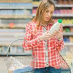 Woman examining a bottle in a grocery store