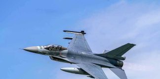 Jet fighter flying through clear blue sky.