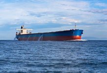 A large cargo ship sailing on the ocean under a blue sky