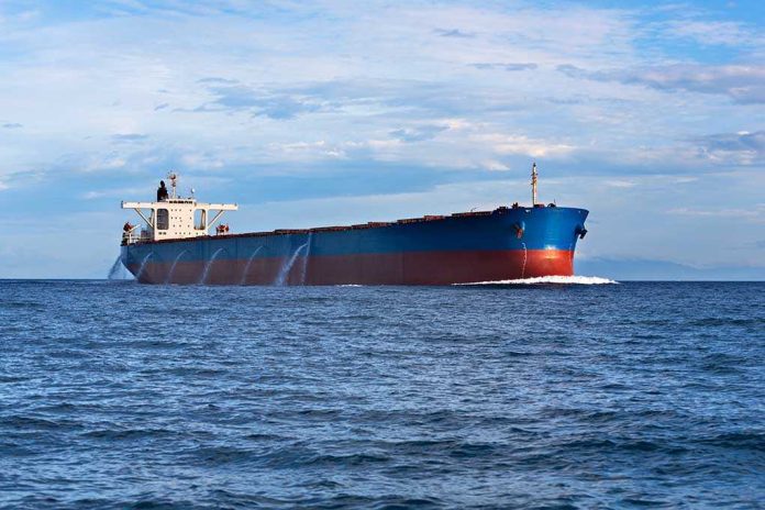 A large cargo ship sailing on the ocean under a blue sky