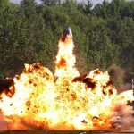 A large explosion with flames and smoke in an outdoor setting