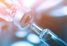 Close-up of a syringe drawing liquid from a vial