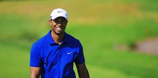 Tiger Woods BODY-Cam Shock Moment A smiling golfer wearing a blue shirt and white cap on a green golf course