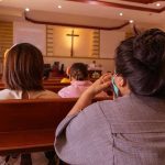 Catholic Church Files BANKRUPTCY After Settlement Payments People sitting in church pews during service.