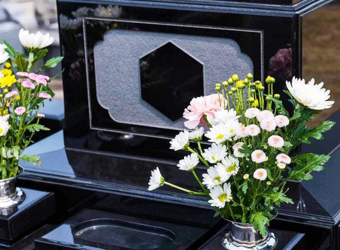 1796581054-2 Colorful flowers on a black tombstone.