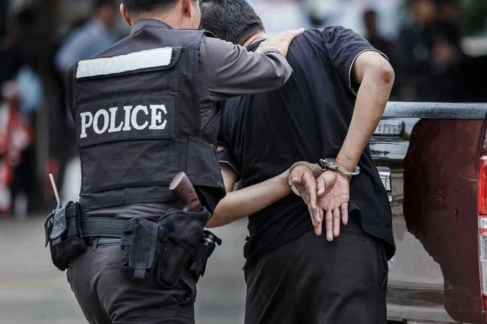 693957643 Police officer arrests handcuffed person.