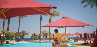 Hero ICE Officer Rescues Drowning Child! Lifeguard overlooking a resort swimming pool with red umbrellas