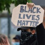 BLM Leader Issues Most RACIST Statement Yet! Person holding Black Lives Matter sign at protest.