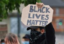 Person holding Black Lives Matter sign at protest.