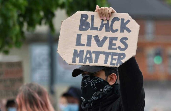 shutterstock_1750395071 Person holding Black Lives Matter sign at protest.