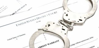 Plane Hijacker Awaiting Deportation FREED by Dem Judge Handcuffs on top of an arrest warrant document.