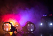 Handcuffs on a surface with police cars and flashing lights in smoky darkness