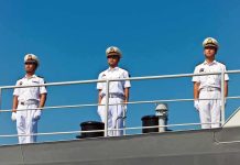 three naval officers in white uniforms standing on a ship deck
