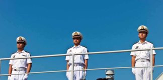 three naval officers in white uniforms standing on a ship deck