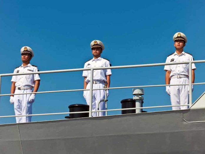 three naval officers in white uniforms standing on a ship deck