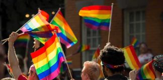 Crowd waving rainbow flags at an outdoor event