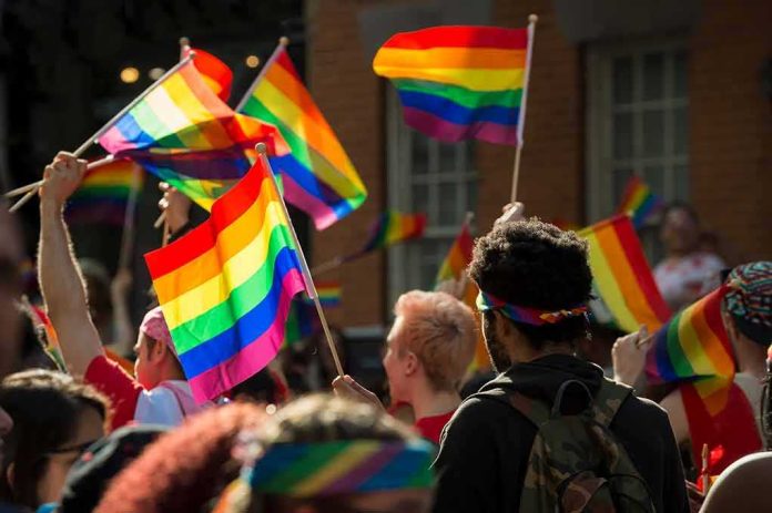 Crowd waving rainbow flags at an outdoor event