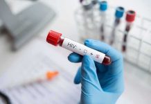 Gloved hand holding a blood sample tube labeled for HIV test