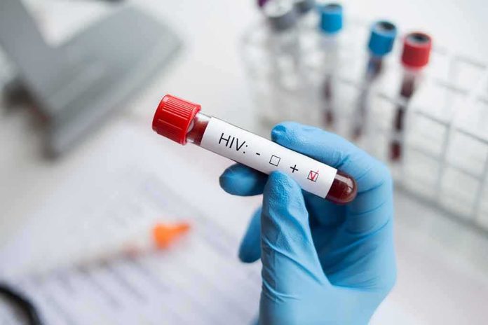 shutterstock_1224734254 Gloved hand holding a blood sample tube labeled for HIV test