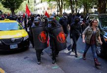 masked protesters march with shields on a city street