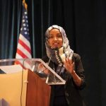 Woman in hijab speaking at a podium