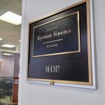 Senator Bails Boyfriend Out Of Jail Office door plaque with gold trim outside a glass-walled conference room