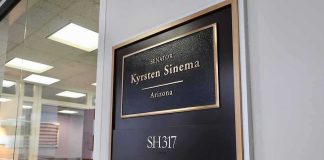Office door plaque with gold trim outside a glass-walled conference room