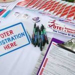 Dems Push to LOWER Voting Age Voter registration table with forms, pens, and informational materials