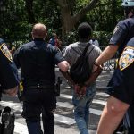 Man Caught Outside Supreme Court With Guillotine Police escort a handcuffed man across a city street