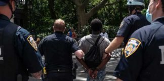 Man Caught Outside Supreme Court With Guillotine Police escort a handcuffed man across a city street