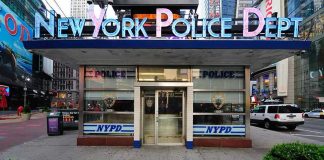 NYPD precinct building with signs on a city street
