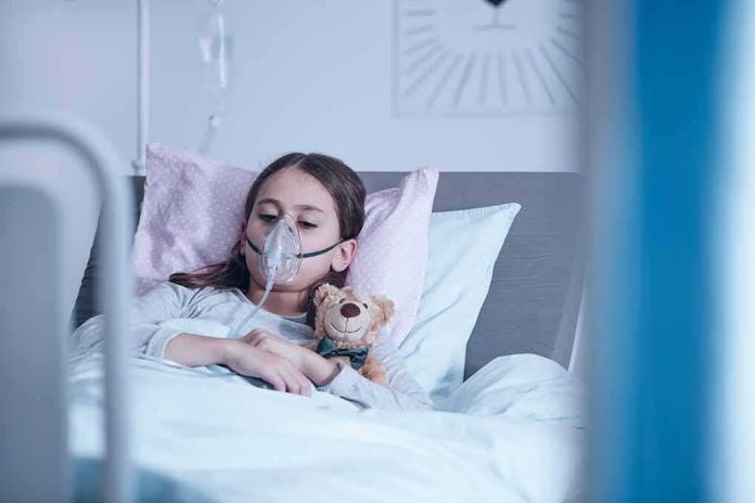 shutterstock_1019243068 Child in hospital bed with oxygen mask holding teddy bear