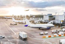 Airplanes at airport gates during sunset with ground vehicles and jet bridges