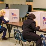 Voters seated at booths filling out ballots in a polling place