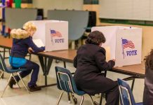 Voters seated at booths filling out ballots in a polling place