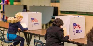 Voters seated at booths filling out ballots in a polling place