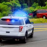 Police SUV with flashing lights at roadside crash scene