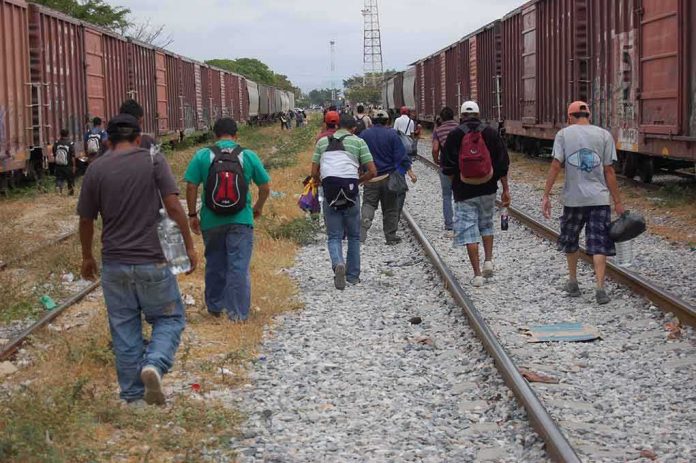 shutterstock_1119750086 Group of people walking along railroad tracks between freight trains
