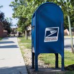 Blue USPS mailbox on a suburban sidewalk