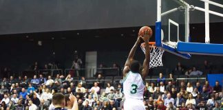 Basketball player dunks the ball in a crowded arena