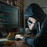 Kristi Noem’s Household Rocked By NEW Scandal! Person in hoodie using computer and phone at desk
