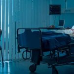hospital room with child in bed and adult sitting nearby