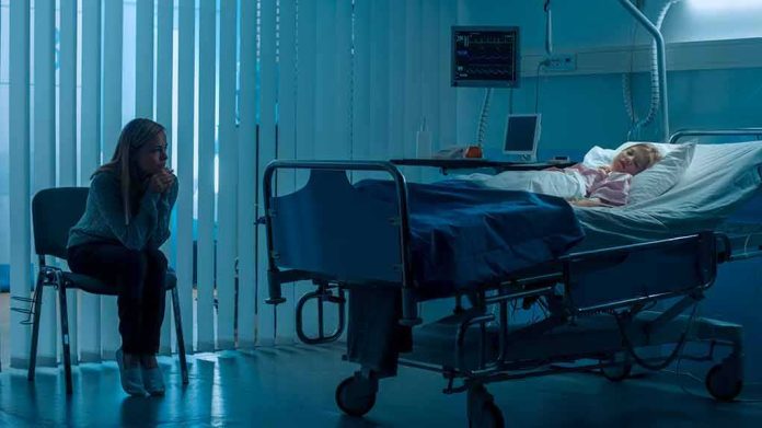 hospital room with child in bed and adult sitting nearby
