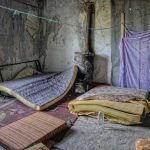 Abandoned room with torn mattresses and a rusty stove