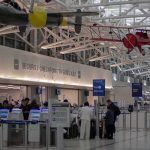 Airport Chaos – Undercover Agents Tackle Traveler! airport security checkpoint with passengers and hanging vintage airplanes