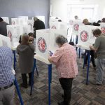 Voters fill out ballots at polling booths in a busy voting room