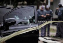 Car door with bullet holes at a taped-off crime scene