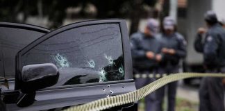 Car door with bullet holes at a taped-off crime scene