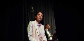 Woman in a white suit sitting backstage with a folder